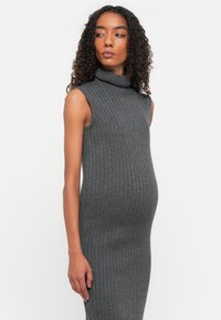 Pilkos juostelės megztas be rankovių suknelė su aukštu kaklu ir prigludusia forma, pabrėžianti apvalų pilvą. Lygus paviršius.