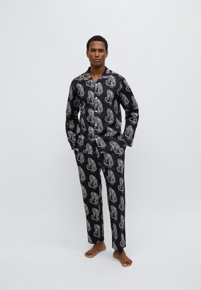 Set di pigiami nero con motivo di elefanti bianchi. Realizzato in tessuto liscio, comprende una camicia con colletto e pantaloni a gamba dritta.