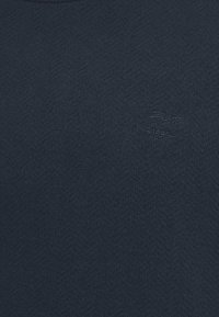 Navyblauer, strukturierter Pullover aus weichem Stoff, mit Rundhalsausschnitt und einem geprägten Markenlogo auf der Vorderseite.