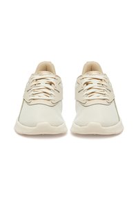 Kreminės spalvos sportiniai batai su tinklelio viršumi, apvalia nosimi, plokščiais raišteliais ir minimaliais prekės ženklais. Lengvo dizaino su paminkšlintu padu.