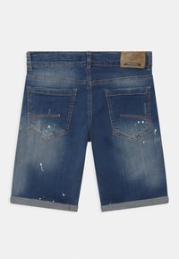 Tummansiniset farkkushortsit, joissa on käärityt lahkeet, kaksi takataskua, maalitahroja ja ruskea nahkainen tuotemerkkipäällyste vyötäröllä.