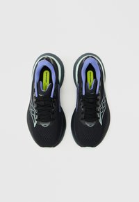 Μαύρα παπούτσια τρεξίματος Saucony με μοβ εσωτερική επένδυση, λευκές λεπτομέρειες στη σόλα και ένθετα φλούο κίτρινα πέλματα με την ένδειξη «NEUTRAL», σε όψη από πάνω.