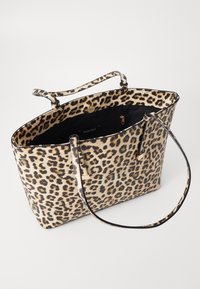 Sac fourre-tout imprimé léopard avec accents et poignées noirs. Intérieur spacieux, avec une poche zippée. Fabriqué en matériau texturé.