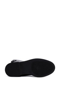 Zwarte schoenen met een getextureerde rubberen zool. Heeft een glad bovenwerk en een ronde neus. Inclusief een verstelbare banddetail. Geen zichtbare patronen.
