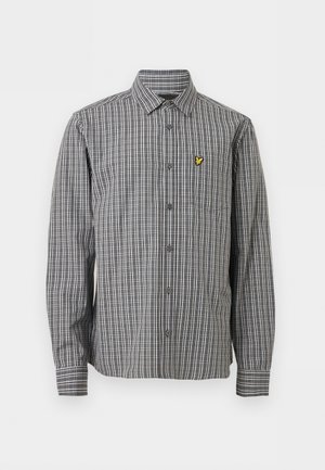 Chemise à manches longues boutonnée à carreaux noirs et blancs avec col et petit logo d'oiseau jaune sur la poche poitrine gauche.