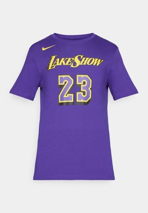 Paarse T-shirt met korte mouwen, met gele tekst "Lake Show" en nummer 23, voorzien van een kleine gele Nike-swoosh op de linkerborst.