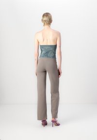 Denimu strapless tops, pelēki pieguļoši bikses un violeti papēžu sandales. Gluda tekstūra ar brīvu piegriezumu un taisnu kāju dizainu.