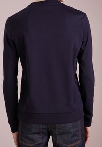 Dunkelblaues Sweatshirt, lange Ärmel, Rundhalsausschnitt, glatte Textur, geripptes Bündchen und Bündchen an den Ärmeln, mit einem schlichten Design ohne sichtbare Logos.
