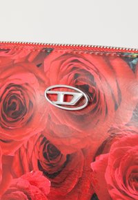 Clutch floreale rossa con finitura lucida, caratterizzata da un dettaglio hardware ovale in argento. Decorata con grandi rose vivaci. Chiusura con zip.
