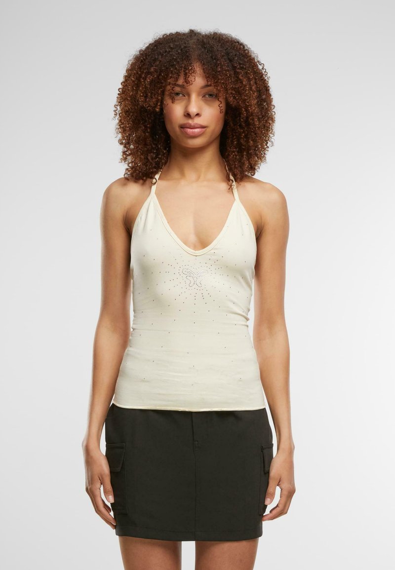 Lys beige halterneck top med dyb V-udskæring, der har et centralt dekorativt mønster med små rhinsten, parret med en mørk cargo nederdel.