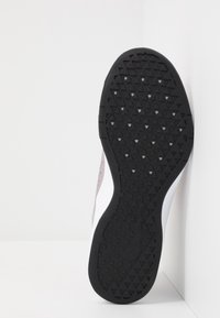 Semelle en caoutchouc noire avec un motif triangulaire texturé, dotée d'une semelle intermédiaire blanche et d'une partie supérieure rose clair. Design simple et ergonomique.