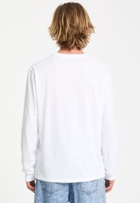 Langärmliges weißes T-Shirt aus weicher Baumwolle, mit runder Ausschnitt und lockerer Passform, von hinten betrachtet.
