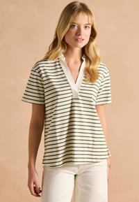 Lühikeste varrukate ja triibulise disainiga polo särk kreemja ja rohelise värviga, millel on nurgatagune krae ja mugav lõige. Pehme, kudumifaas ja külgedel lõhikud.