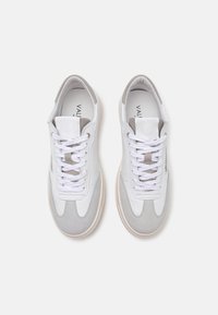 Hvide og grå sneakers med læder- og ruskindsmaterialer, der har et snørebåndsdesign, rund tå og branding på tungen.