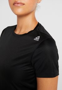 Svart tränings t-shirt tillverkad av mjukt, lätt material. Har rund halsringning, korta ärmar och en liten vit Reebok-logotyp på axeln.