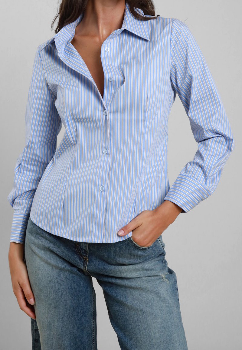 Camicia azzurra chiaro con bottoni, caratterizzata da strisce verticali bianche e azzurre chiare, con colletto a punta e maniche lunghe.
