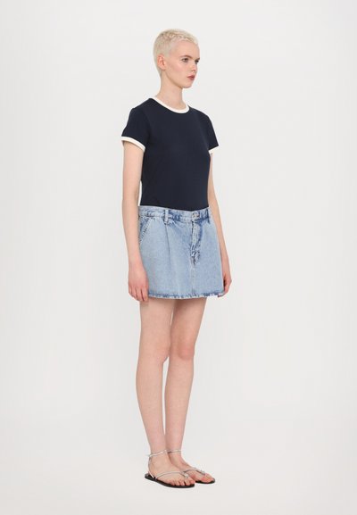 Navy short-sleeve t-shirt with white trim, paired with a light blue denim mini skirt with a front button closure and belt loops. Flat sandals.