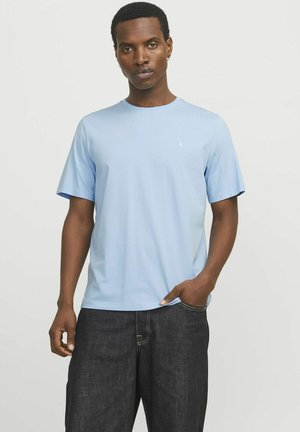 T-shirt en coton bleu clair à manches courtes et col rond, avec un petit logo sur la poitrine et une coupe décontractée. Porté avec un pantalon en denim noir.