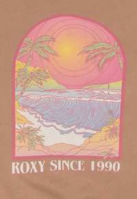Tessuto marrone con un design grafico che presenta palme, onde oceaniche e un tramonto in colori rosa e pastello. Testo: "ROXY DAL 1990."