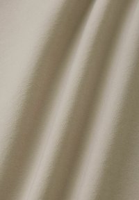 Tessuto beige morbido con trama sottile e pieghe delicate che creano onde verticali morbide.