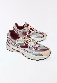 Pantofi sport cu partea superioară din plasă și piele în bej, bordo și argintiu. Prezintă o guler căptușit și o talpă din cauciuc texturată pentru aderență.