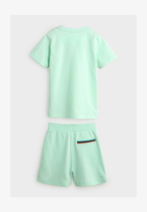 Mintgroene katoen t-shirt met korte mouwen en bijpassende shorts, met een gestreepte zakaccent aan de rechter achterkant van de shorts.