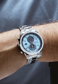 Orologio in acciaio inossidabile argentato con quadrante azzurro chiaro, sottodial neri e funzioni cronografo. Bracciale di stile con maglie lucidate.