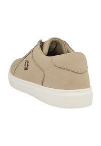 Sneaker in suede beige con suola in gomma bianca. Presenta una punta arrotondata e un piccolo logo marrone sul lato. Texture liscia e design minimale.