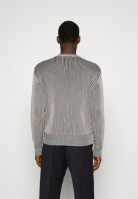 Strickpullover mit vertikalen grauen und marineblauen Streifen, rundem Halsausschnitt, gerippten Bündchen und Saum. Das Material wirkt weich mit einer strukturierten Oberfläche.