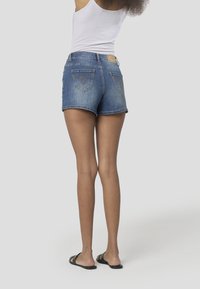 Jeansshorts in Hellblau mit zwei Gesäßtaschen mit Ziernähten, einem umgeschlagenen Saum und einem braunen Lederetikett der Marke an der Taille.