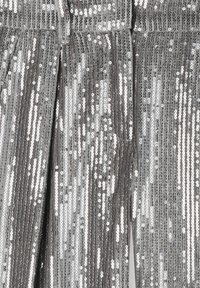 Tessuto di paillettes argento con strisce verticali, caratterizzato da una superficie liscia e riflettente. Presenta un design con vita nella parte superiore.