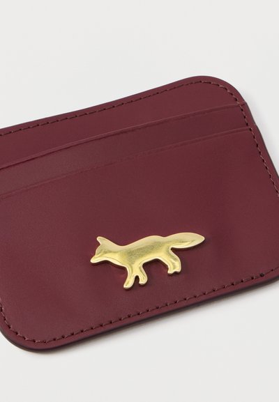 Καρτοθήκη από βουργουνδίζον δέρμα με μεταλλικό χρυσό έμβλημα αλεπούς, τρεις θήκες για κάρτες και λεία υφή.
