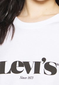 Weißes Baumwoll-T-Shirt mit schwarzem "Levi's"-Logo und dem Text "Seit 1873" darunter. Rundhalsausschnitt mit kurzen Ärmeln.