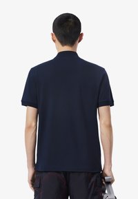 Námořnická polo tričko s klasickým límečkem, krátkými rukávy a hladkou texturou, s jednobarevným provedením a uvolněným střihem.