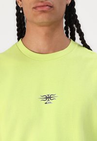 Lime green short-sleeve t-shirt made of cotton, featuring a small dark logo design on the chest and a classic crew neck.