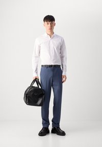 Weißes Langarmhemd, blaue maßgeschneiderte Hose, schwarze Ledertasche und klobige schwarze Schuhe. Sauberes Design mit glatten Texturen und strukturierten Formen.