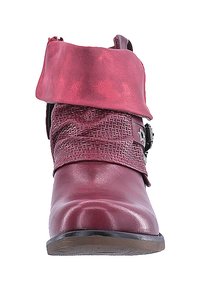 Botín de tobillo de piel sintética roja con una banda tejida texturizada y hebilla decorativa. El puño es brillante y se pliega sobre el tobillo. Suela de goma plana.