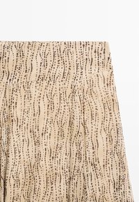 Beige Stoff mit einem wellenförmigen Muster in Dunkelbraun. Verfügt über ein plissiertes Design und eine glatte Textur, geeignet für leichte Kleidungsstücke.