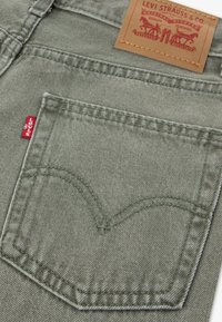 Πράσινα τζιν από τζιν ύφασμα με πίσω τσέπη που διαθέτει ένα ξεχωριστό καμπυλωτό σχέδιο ραφής και μια κόκκινη τ αμπέλα Levi's προσαρτημένη. Περιλαμβάνεται δερμάτινο ταμπελάκι της μάρκας.