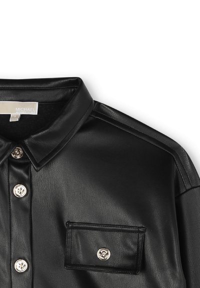 Chemise en similicuir noir avec un col à rabat, fermetures à boutons argentés et une poche poitrine. Texture lisse avec des détails aux épaules.