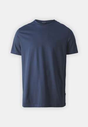 T-shirt en coton bleu marine avec un col rond, des manches courtes et un logo en relief discret sur la poitrine. Texture lisse et légère.