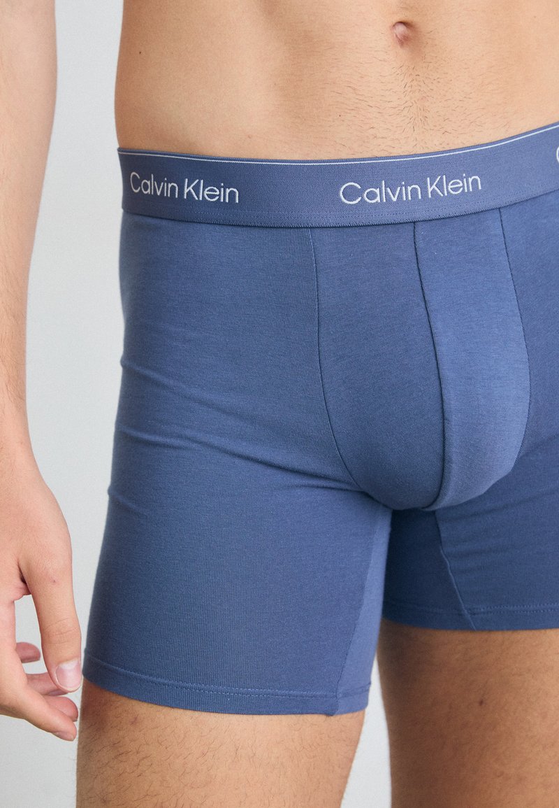 Boxers en coton mélangé bleu avec un design ajusté et une taille élastique arborant le logo Calvin Klein en blanc.