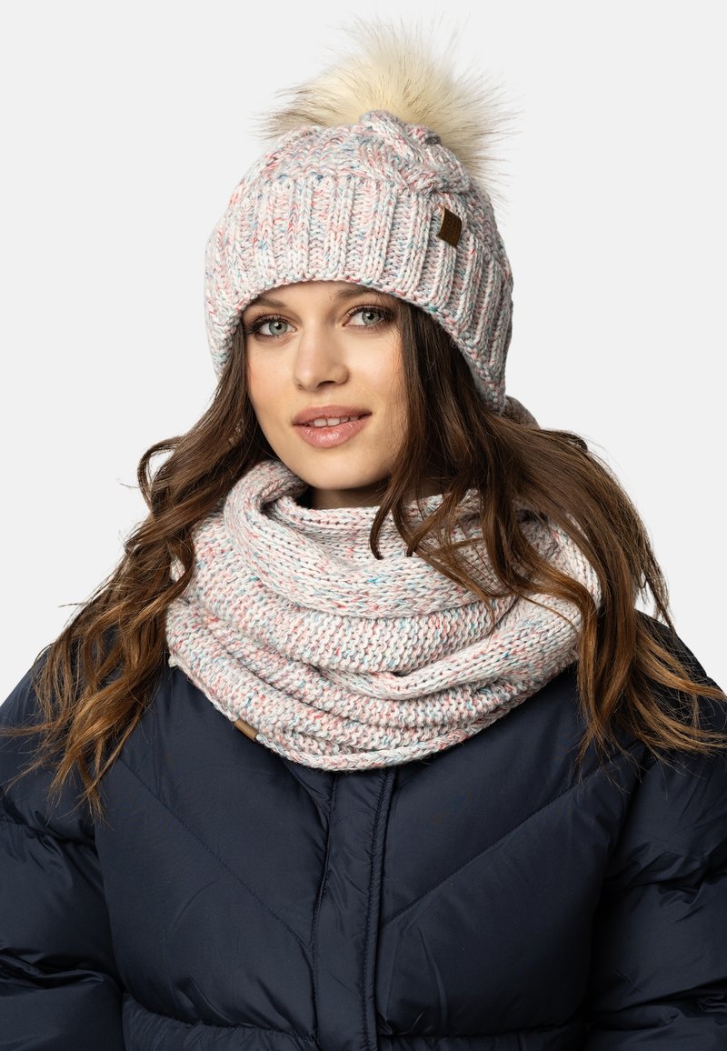 Bonnet d'hiver en tricot et écharpe infinie, en fil doux de couleur rose clair et blanc avec des éclats de bleu, le bonnet possède un pompon en fausse fourrure sur le dessus.
