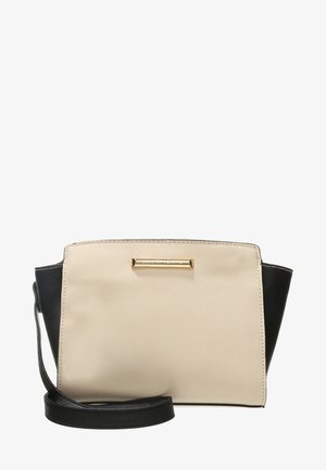 Sac bandoulière beige et noir avec une finition texturée, une plaque logo rectangulaire dorée, et une sangle noire réglable.