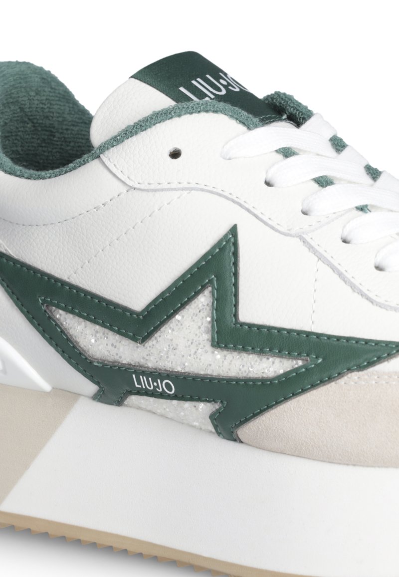 Witte sneaker met groen ster ontwerp, groene binnenvoering, witte veters en beige suède neuskap detail.