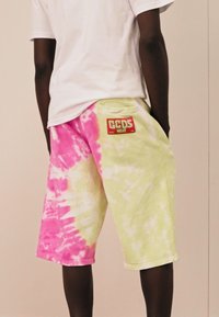 Tarka festésű sortok élénk rózsaszín és lime zöld árnyalatokkal, puha anyagból készült, hátsó zsebében foltlogóval.