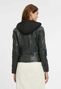 Zwarte leren jack met een zwarte hoodie, aansluitend ontwerp, textuurafwerking, accentstiksel en geplooide mouwdetails.