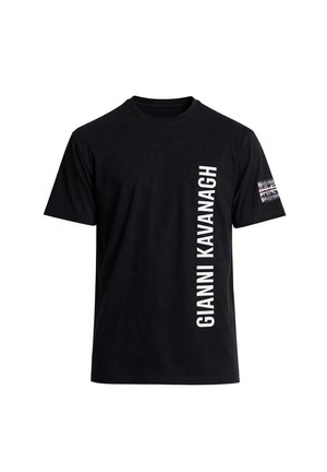 Camiseta negra de manga corta con texto blanco vertical "GIANNI KAVANAGH" en el lado derecho del frente y una pequeña bandera del Reino Unido en la manga izquierda.