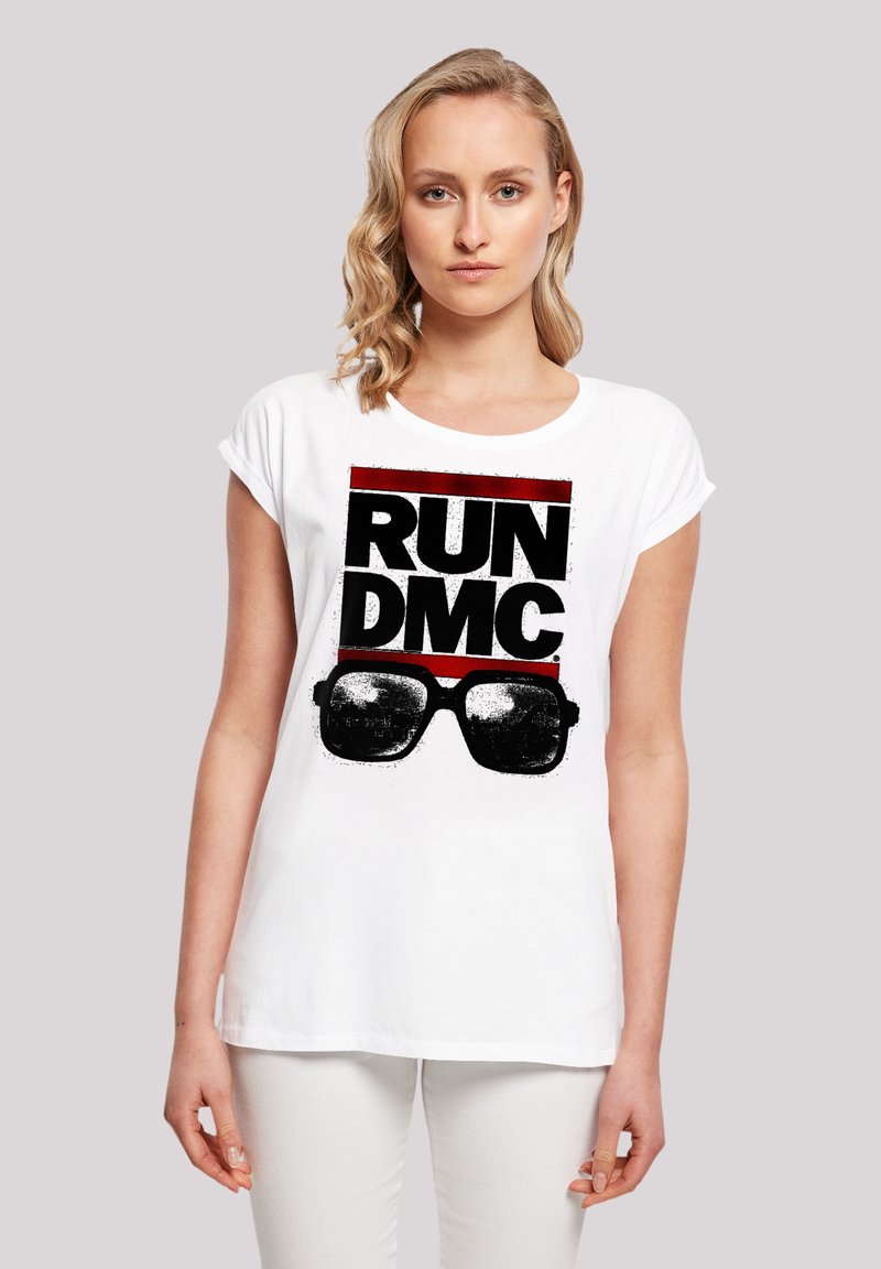 Weißes Baumwoll-T-Shirt mit einem auffälligen schwarzen und roten Grafikdruck, der "RUN DMC" mit Sonnenbrille zeigt. Kurze Ärmel und lockere Passform.