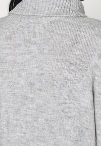Maglione grigio a collo alto realizzato in morbido tessuto a maglia, con colletto a costine e vestibilità comoda, caratterizzato da una superficie liscia e senza motivi visibili.